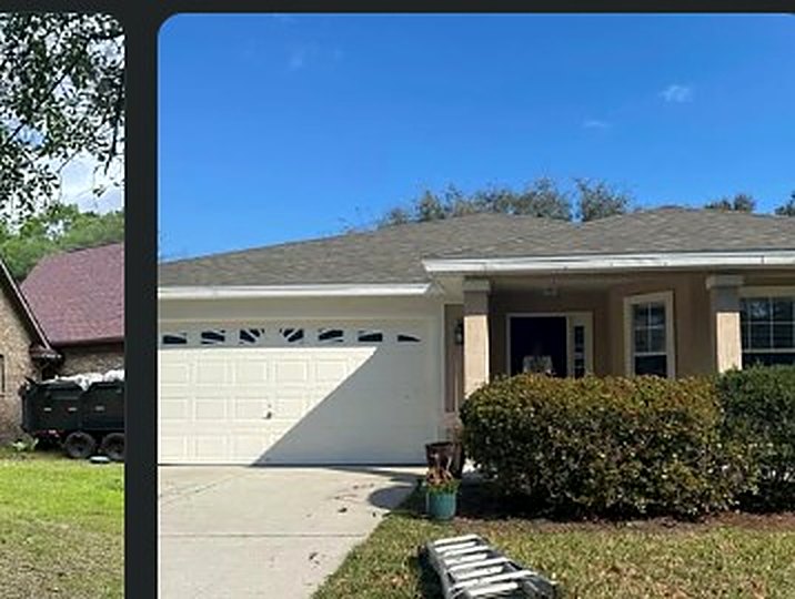 Two-car-garage home with a tidy gray shingle roof and fresh landscaping